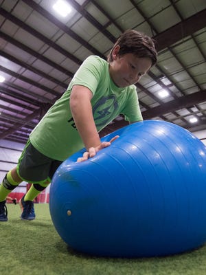 Aidan Quintana (10) completes push-ups using a ball during a training session with Sports Specific Training at Slim's Sports Complex in Middletown.