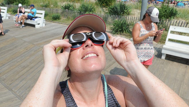 Bridget McGeady, of Baltimore, looks through glasses at the solar eclipse that was watched by many on the boardwalk at Rehoboth Beach on Monday, Aug. 21.