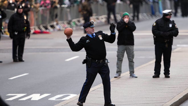 A Philadelphia police officer tosses a football into the crowds along the Super Bowl LII Championship parade route on broad street.