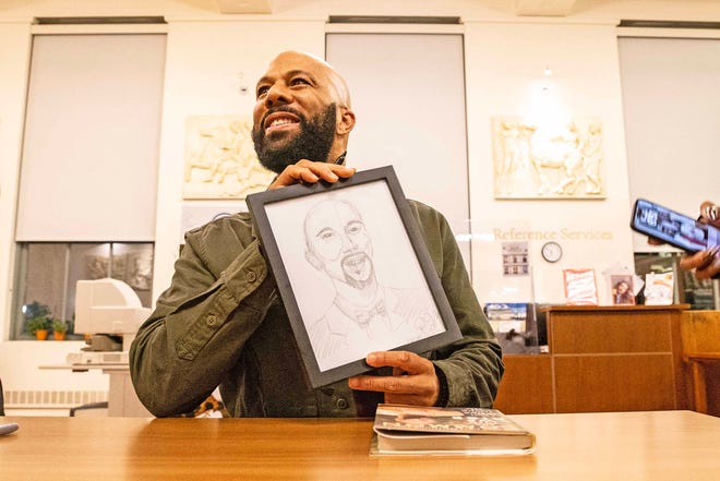 Common, rapper, actor, writer and activist, holds up a drawing of himself gifted by a fan during the book signing of his book And Then We Rise: A Guide to Loving and Taking Care of Self at the Wilmington Public Library on Friday, Jan 26, 2024. A capacity crowd of approximately 350 people attended.