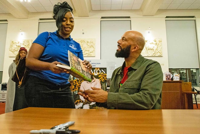 Common, rapper, actor, writer and activist, chats with and prepares to sign his book for a fan during a book talk and signing event for And Then We Rise: A Guide to Loving and Taking Care of Self at the Wilmington Public Library on Friday, Jan 26, 2024. A capacity crowd of approximately 350 people attended.