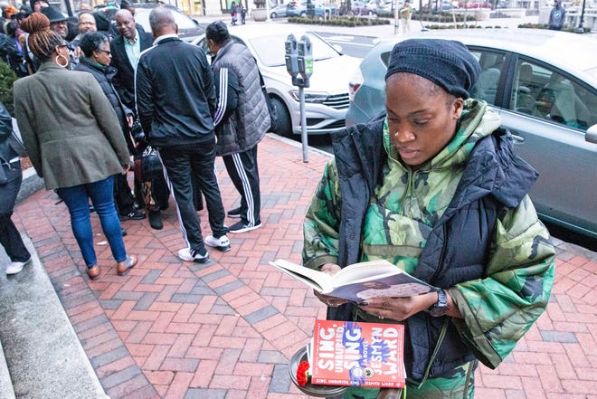 Damali Thomas reads a book by Common as she stands in line to enter a book talk and signing event for And Then We Rise: A Guide to Loving and Taking Care of Self a book by Common, rapper, actor, writer and activist, at the Wilmington Public Library on Friday, Jan 26, 2024. A capacity crowd of approximately 350 people attended.