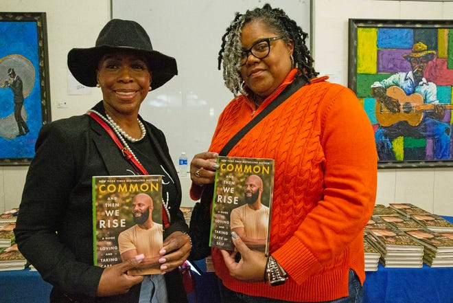 Fans buy and pose with And Then We Rise: A Guide to Loving and Taking Care of Self a book by Common, rapper, actor, writer and activist, during a book talk and signing event at the Wilmington Public Library on Friday, Jan 26, 2024. A capacity crowd of approximately 350 people attended.