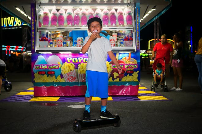 Connor Maloney, 9, of Houston rides around in hoover board enjoying some cotton candy at the Delaware State Fair on Monday night.