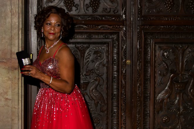 Sheila Marlowe a full-length red Jovani ball gown with embellished square glitter sequin top with red crystal and rhinestone earrings and necklace, all from Morgan’s of Delaware; and silver high-heel pumps.