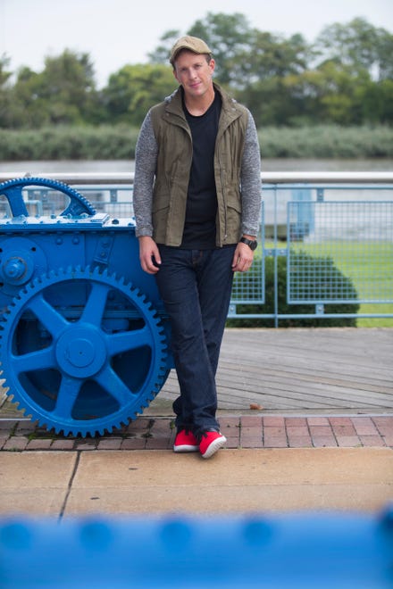 Tim Carr wears a gray and khaki green jacket from The Love Tree; black cotton tee; navy denim jeans by Perry Ellis' and red and black leather Nike Air Jordans.
