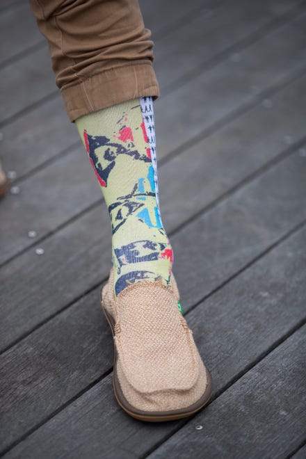 Tim Carr wears yellow Beatles socks from Happy Socks with tan hemp shoes from Sanuk and darker tan pants.