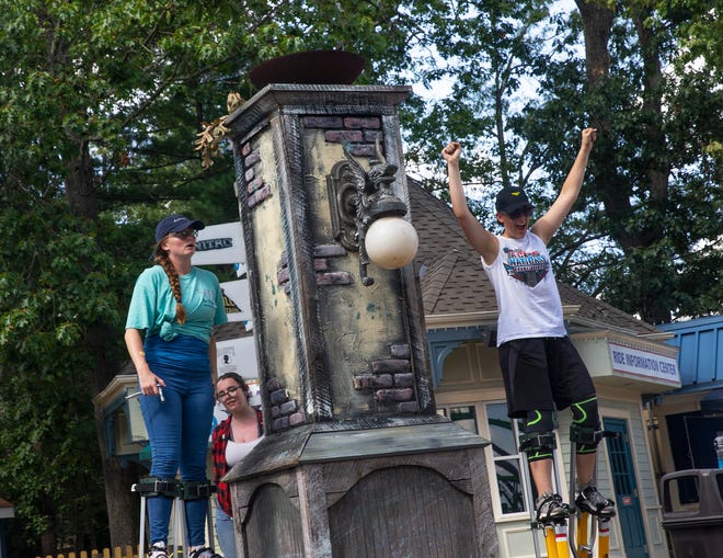 Workers hang street lamps onto columns lining the parkâ€™s main avenue in preparation for Fright Fest.