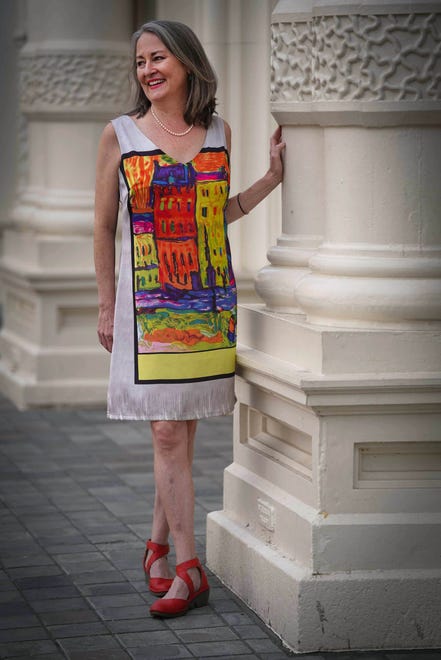 Lucy Clemens wears a silver gray dress with an image of brightly colored painting in a black border, by Sweet Miss, with Fly of London Piat Devil red pumps.