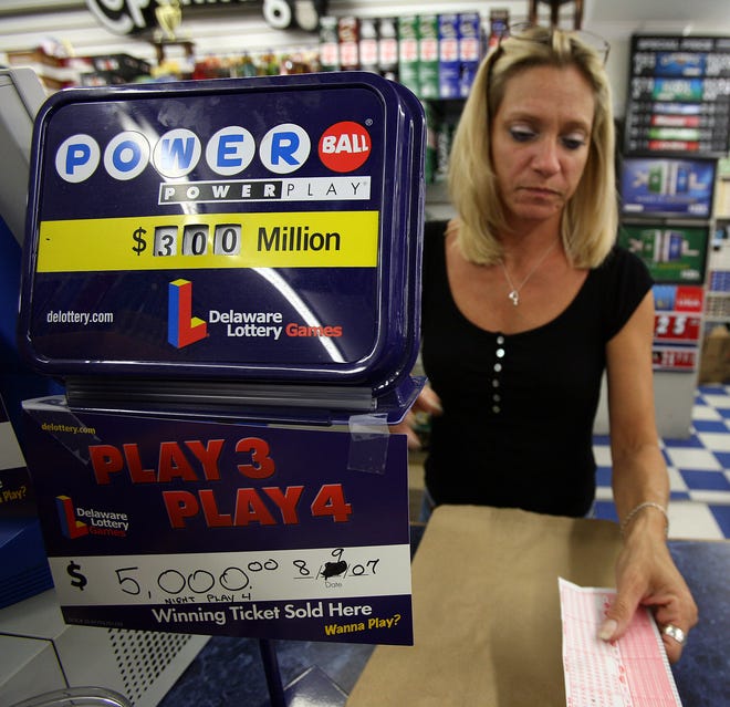 Bev Ward, a store clerk at Airport News in New Castle, sells Powerball lottery on Friday evening. Saturday's drawing of the Powerball will be reaching $300 million.