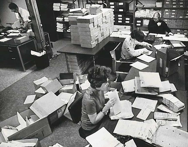 Lottery office workers sort through tickets and boxes while accounting for unsold tickets in 1976.