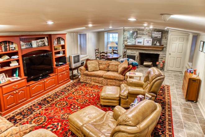 The lower-level family room at 2 Alapocas Drive has a stone fireplace.