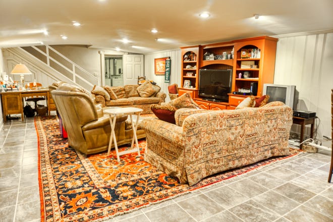 The family room in the basement of 2 Alapocas Drive features tiled floors and a stone fireplace.