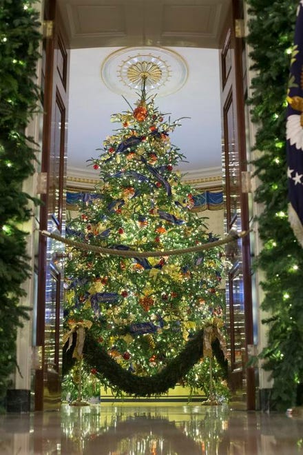 The official White House Christmas tree is dressed in blue velvet ribbon embroidered in gold; as seen from the Cross Hall during a viewing of the 2018 holiday decorations at the White House in Washington, D.C.