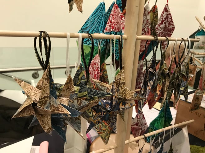 Museum volunteers and others offer their own wares at the Museum's table, including these jeweled Christmas trees and folded paper ornaments.