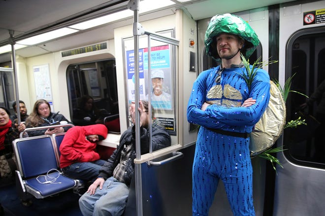 Drew Krause, a member of the Vaudevillians, rides the El to get his makeup for the Mummers Parade, Tuesday, Jan. 1, 2019, in Philadelphia. (David Maialetti/The Philadelphia Inquirer via AP)