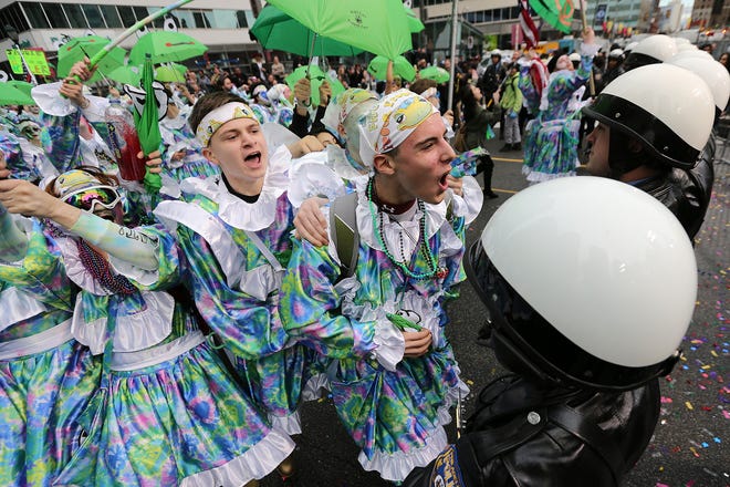 Members of Froggy Carr Wench Brigade strut in front of a row of police at City Hall during the Mummers Parade, Tuesday, Jan. 1, 2019, in Philadelphia. (David Maialetti/The Philadelphia Inquirer via AP)