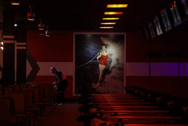 The reinvigorated Bowlero - formerly the AMF Price Lanes - features retro-surfer styling, video panels and blacklight lanes. A worker cleans up after a league event as the theatrical lighting system is engaged for late night.