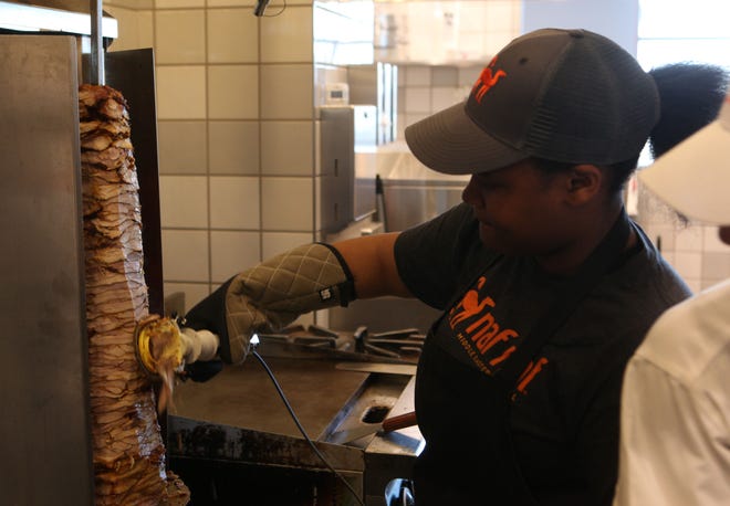 Semaj Smalls cuts chicken shawarma during a soft opening Tuesday afternoon at Naf Naf Grill in Stanton.
