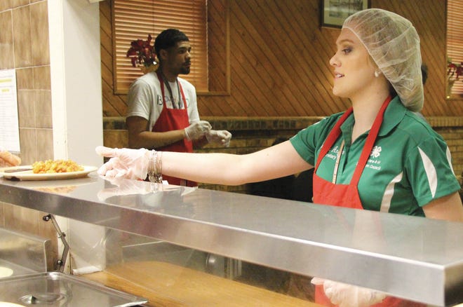 A 4-H member picks up a plate of baked ziti to deliver at the Emmanuel Dining Room in Wilmington.
