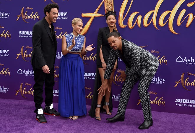 Will Smith (right) playfully covers up daughter Willow Smith ' s legs as Trey Smith (left) and Jada Pinkett Smith look on at the premiere of " Aladdin. "
