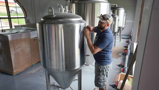 Craig Wensell, CEO and head brewer at Wilmington Brew Works, works on assembling beer making tanks.
