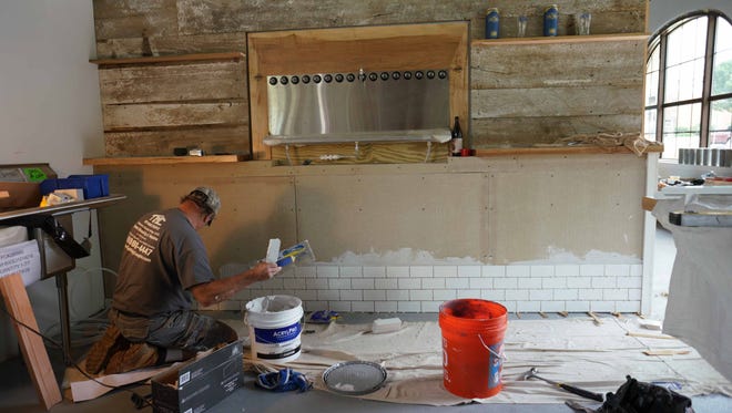 Tiles are placed under future beer taps at Wilmington Brew Works on Miller Road in the long-dormant former site of the Harper-Thiel Electroplating Co., a restored brownfield.