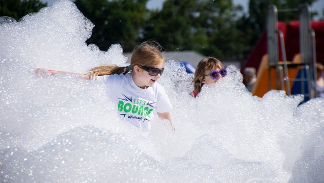 From left, Eleanor Campbell, 6 years of age and Ava Manry, 6 run through the foam bubbles at The Great Inflatable Race held in Shrewsbury, Pa. on Saturday, July 14, 2018.
