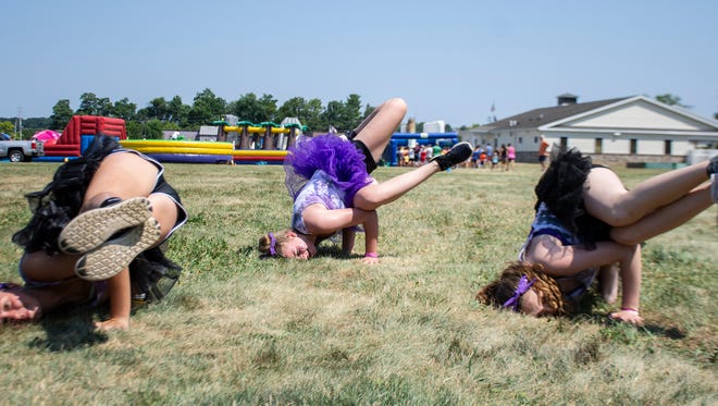 From left, Mackenzie Kirbq, Lane Sipe, Michaela Long perform a headstand at The Great Inflatable Race in Shrewsbury, Pa. on Saturday, July 14, 2018.