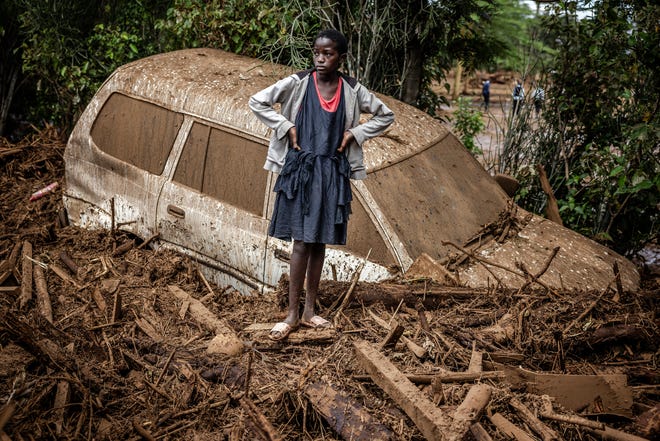 April 29, 2024: A girl looks on next to a damaged car buried in mud in an area heavily affected by torrential rains and flash floods in the village of Kamuchiri, near Mai Mahiu, Kenya. At least 45 people died when a dam burst its banks near a town in Kenya's Rift Valley, police said as torrential rains and floods battered the country.