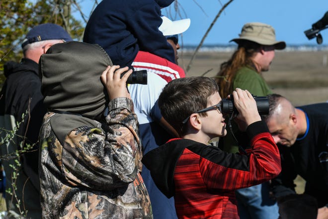 Best friends Charlie Roper, left, and Elijah Goodwin, peer through binoculars to see the rocket launch from the NASA Wallops Island visitor center on Wednesday, April 17, 2019.