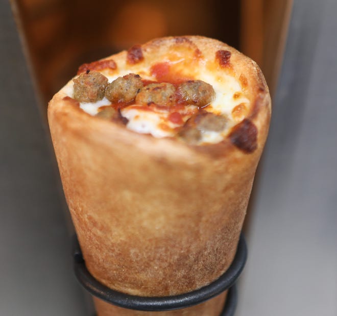 A pizza cone comes out of the oven at a Kono Pizza food truck. The cone-shaped piece of dough is stuffed with cheese, sauce and other toppings before going into a circular rotating oven for three minutes.